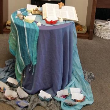 Centre piece of blue cloth with paper boats and candles